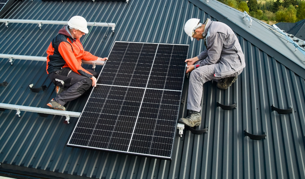 Two men installing solar panels on a roof.
