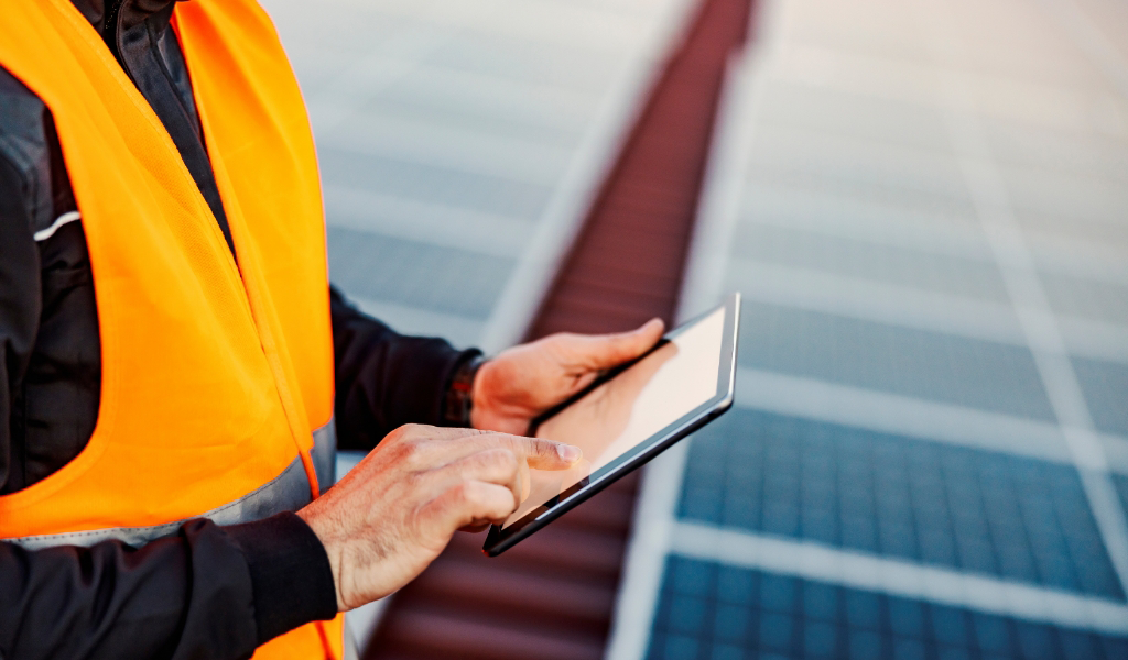 A person using a tablet to monitor solar panels.