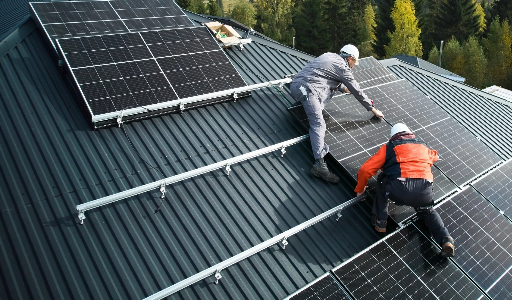 Two professional roofers installing solar panels on a home.
