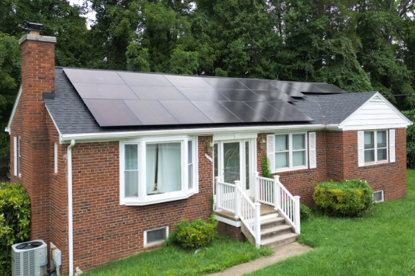 Solar panels on a brick home surrounded by a green lawn.