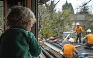 Child watching construction workers re-roof and restore their home.