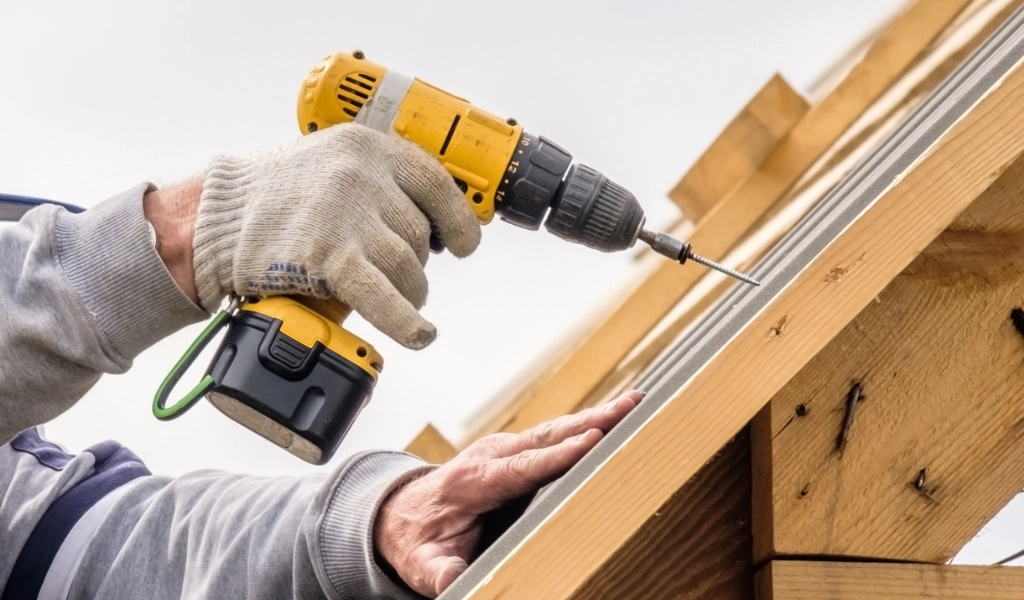 Someone with a drill works on a house.