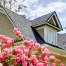 A new roof on a home with pink flowers in the foreground.